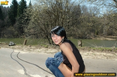 Teen brunette pissing on asphalt path outdoor - N